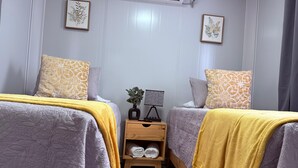 A hotel room with two beds, a nightstand with a lamp, and framed artwork on the walls.