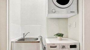 A compact laundry area with a Bosch washing machine, a sink, and a microwave.