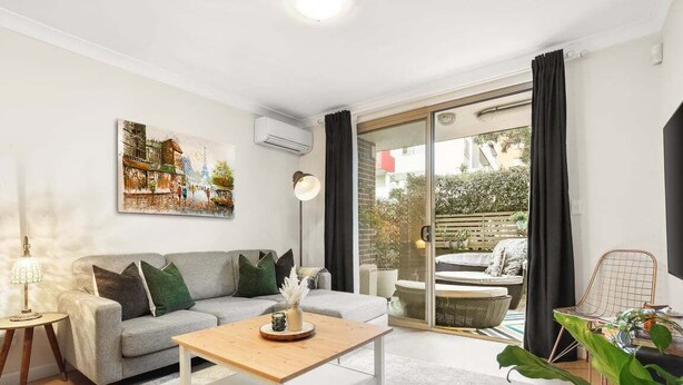 A modern living room with a grey sofa, a wooden coffee table, and a painting on the wall.