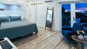 Un dormitorio moderno con una cama, un escritorio con teclado, una silla, un ventilador de techo y un amplio ventanal con vistas.