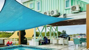 Zona de piscina con terraza de madera, mobiliario exterior y unidades de aire acondicionado.