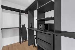 Ein modernes, minimalistisches Zimmer mit Einbauschränken, einer Mikrowelle und einer Kleiderstange.