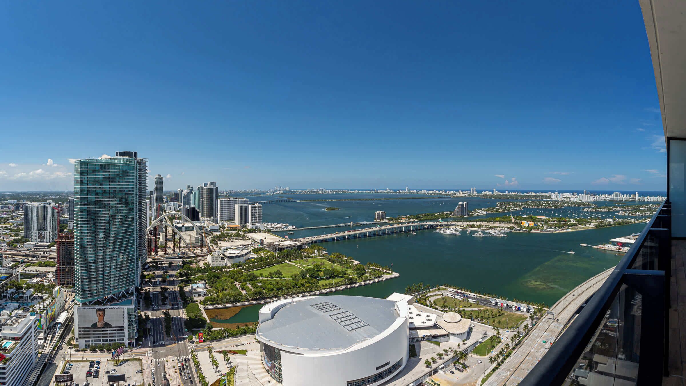 A high-rise building with a modern glass facade, a waterfront promenade, and a distinctive circular building with a dome.
