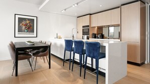 Ett modernt kök med en central köksö, barstolar och ett matbord med stolar.