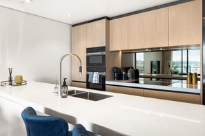 A modern kitchen with a stainless steel sink, a built-in oven, and a coffee machine. - Wynyard Quarter Executive Apt – 3BR Waterfront Living (Auckland City)