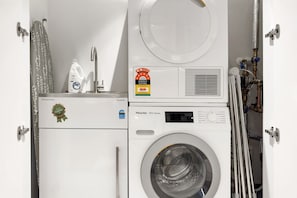 Ein platzsparender Wascher- und Trockner-Kombination mit sichtbarer Energieeffizienzklasse, Bedienfeld und Warmwasserbereiter.