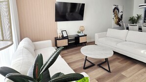 Un salon moderne avec un canapé, une table basse, un téléviseur et une plante.