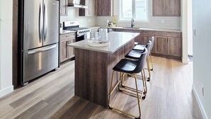 Une cuisine moderne avec des meubles en bois, des appareils en acier inoxydable et un îlot central doté de tabourets de bar.