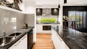 A modern kitchen with a black marble countertop, white cabinetry, and a central island with a built-in oven.