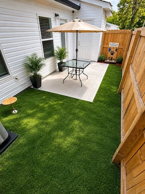 Un patio trasero con una mesa, una zona para mascotas y una valla de madera.