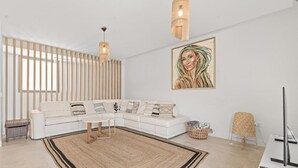 Een moderne woonkamer met een witte modulaire bank, een ronde salontafel, een groot abstract schilderij en een geweven vloerkleed.