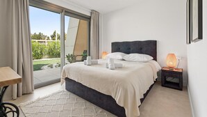 Een slaapkamer met een bed, nachtkastje, tafel en uitzicht op de omgeving.
