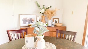 A round dining table with a decorative coaster, a white vase with a plant, and a white container with text.