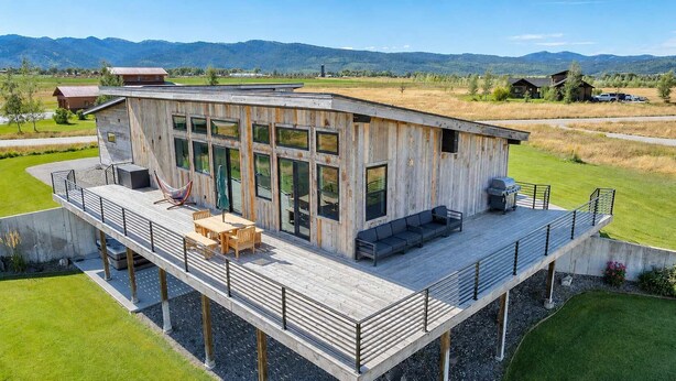 A modern wooden cabin with a deck, large windows, and a view of the surrounding landscape. - Teton Homestead: Shambala Private Mountain Retreat (Victor)