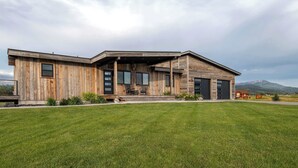 A modern wooden house with a covered porch, large windows, and a well-maintained lawn. - Teton Homestead: Shambala Private Mountain Retreat (Victor)