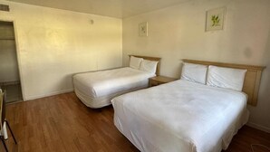 Una habitación con dos camas, piso de madera y una mesita.
