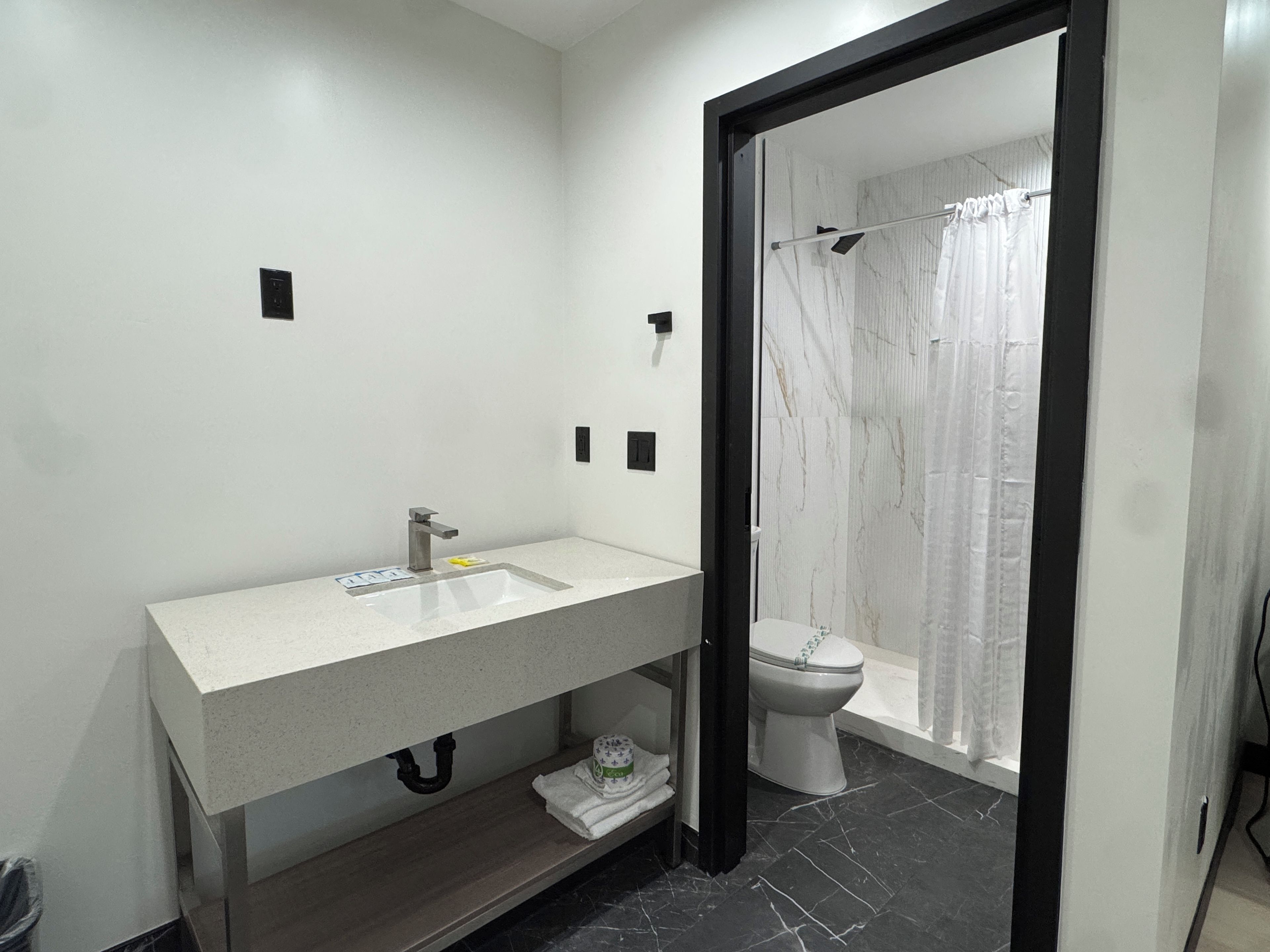 Un baño moderno con un lavamanos blanco, un inodoro y una zona de ducha.