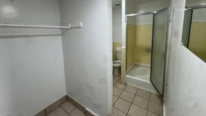 Un baño con ducha, inodoro y cabina de ducha con paredes de vidrio.