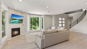 Una sala de estar moderna con chimenea, un televisor de pantalla plana grande, un sofá y una escalera.