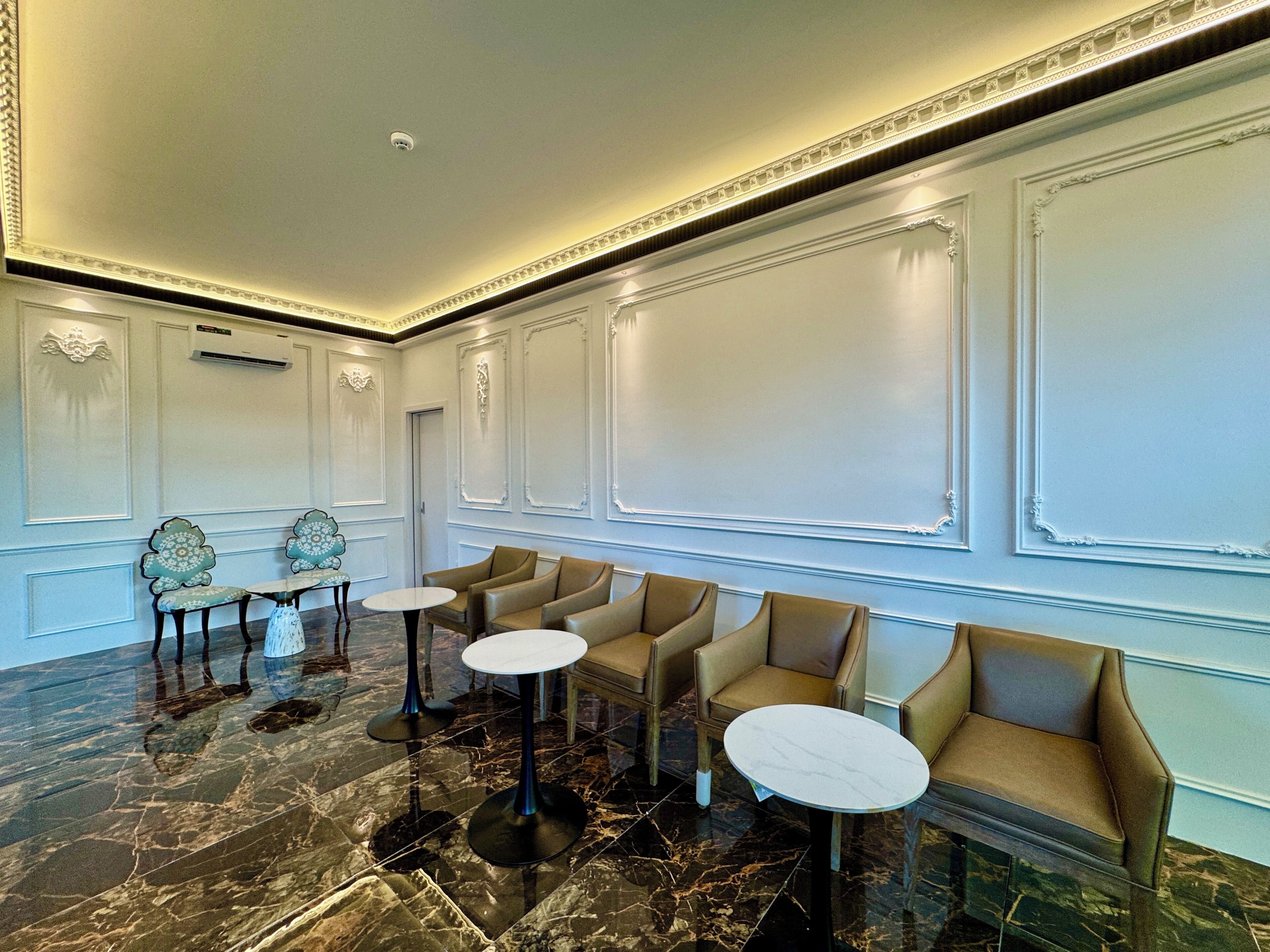 A spacious lobby with marble flooring, multiple seating areas, and decorative moldings.