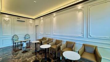 A spacious lobby with marble flooring, multiple seating areas, and decorative moldings.