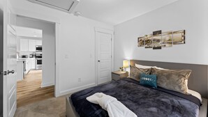 A bedroom with a bed, bedside table, lamp, and artwork on the wall. - Modern Charlotte Retreat Near Uptown (Charlotte)