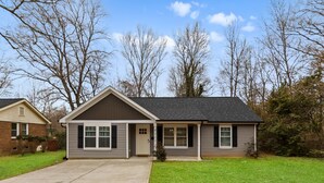 A single-story house with a front porch, a driveway, and a lawn. - Modern Charlotte Retreat Near Uptown (Charlotte)