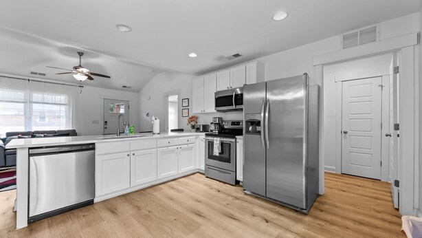 A modern kitchen with white cabinets, stainless steel appliances, a dishwasher, and a ceiling fan. - Modern Charlotte Retreat Near Uptown (Charlotte)