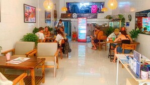 A cafe with wooden furniture, a TV screen, and a sign for a second-hand clothes shop. - Social Backpacker Hostel & Rooftop Bar (Battambang)