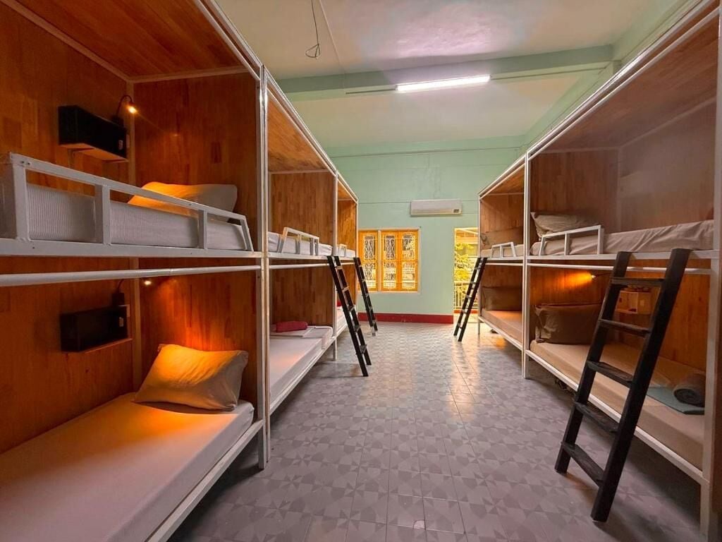 Une chambre avec des lits superposés, des murs en bois, un sol carrelé et une fenêtre donnant sur un beau paysage.