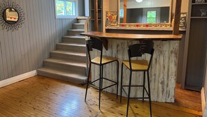 Un espace bar avec un miroir, des tabourets et un escalier.
