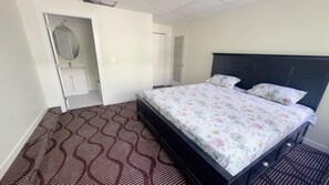 Een slaapkamer met een bed, een kledingkast, een spiegel en een deur.
