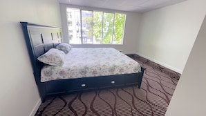 A room with a bed, a window, and a patterned carpet. - Entire condo in White Rock, Canada (White Rock)