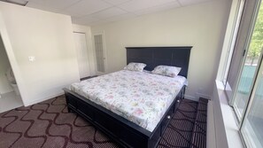 Een slaapkamer met een bed, een raam en een deur.