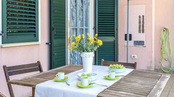 Un tavolo apparecchiato con una tovaglia bianca, piatti verdi e un vaso di fiori gialli.