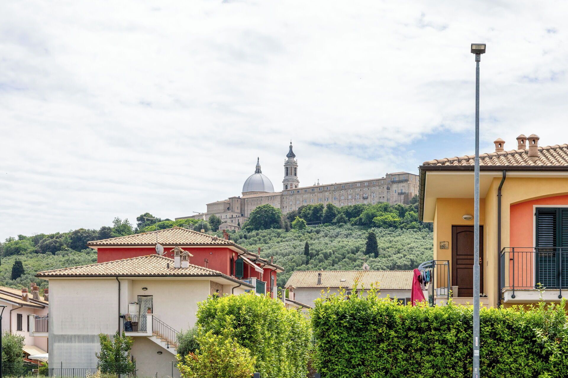 Un quartiere residenziale con case, un lampione e un grande edificio con una cupola sullo sfondo.