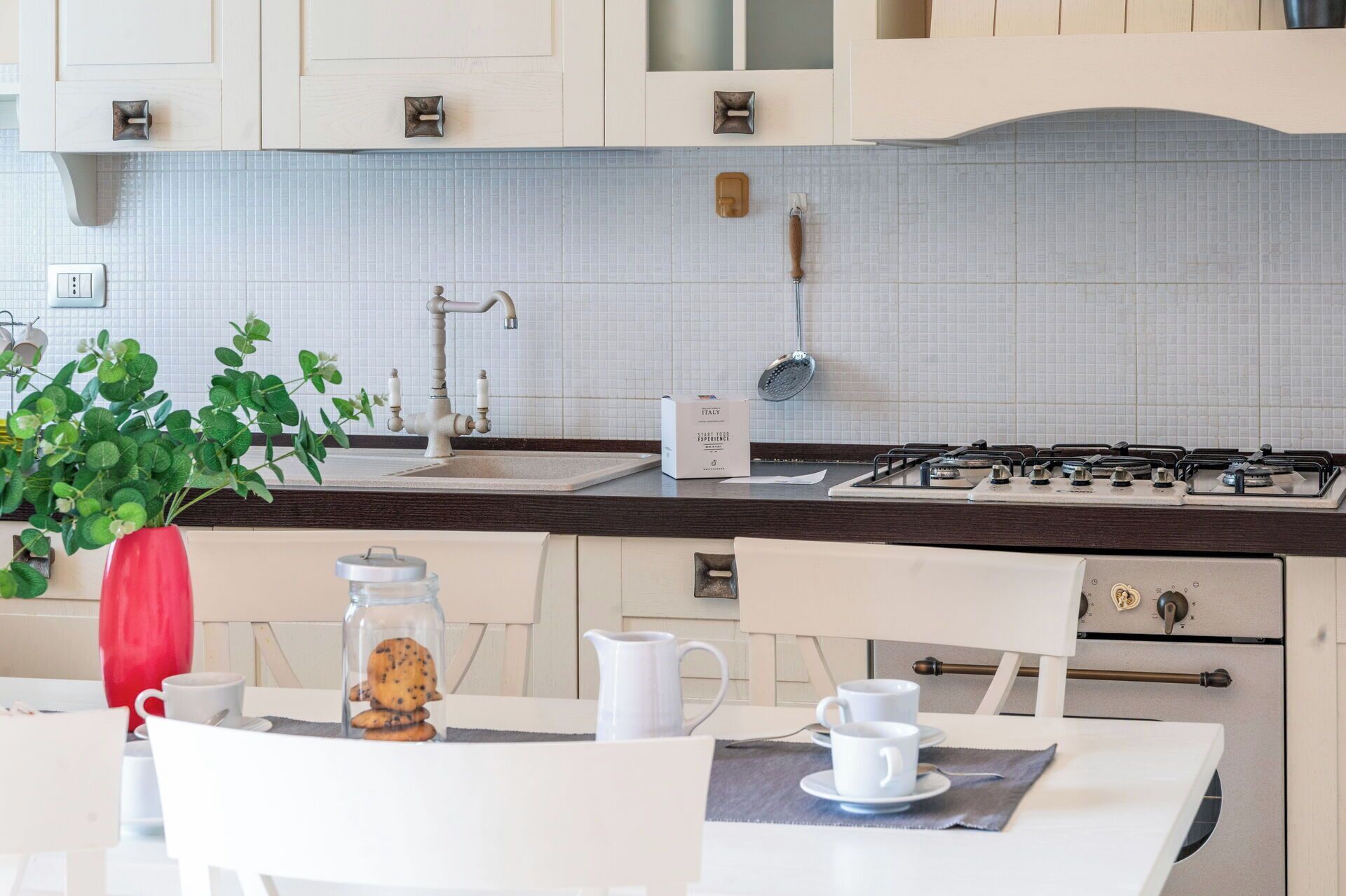 Una cucina con piano cottura a gas, lavello e rivestimento a parete.