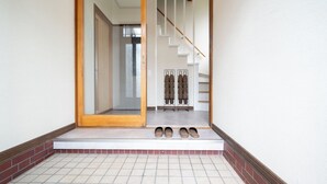 Ein Flur mit Fliesenboden, einer Holztür und einer Treppe mit Holzgeländer.