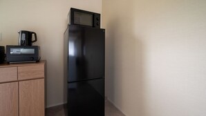 A black refrigerator with a microwave on top, a coffee maker, and a wooden cabinet below. - Furano Harmony House (Furano)