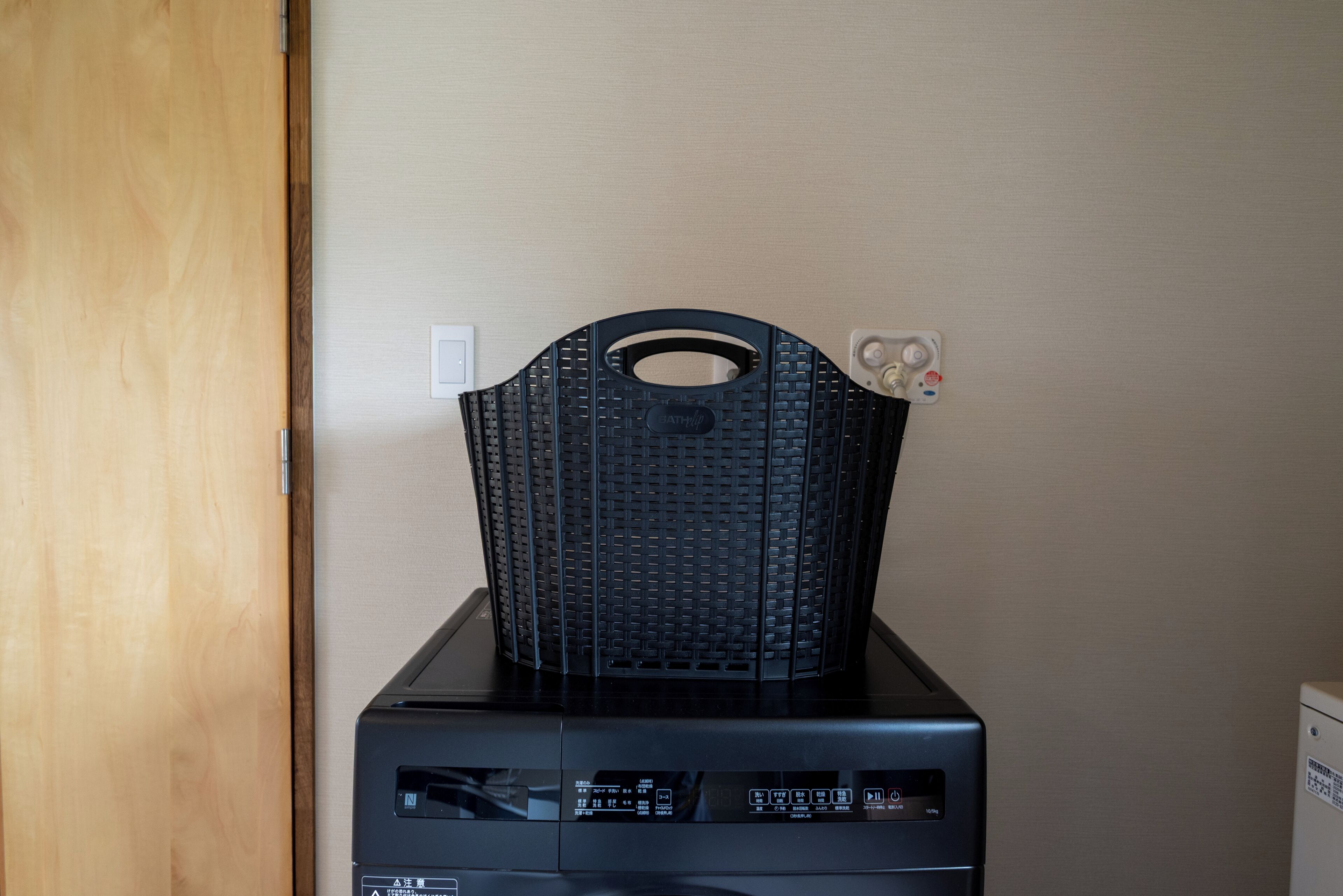 A black appliance with a handle on top, a control panel with various buttons and indicators, and a small white device attached to the side.