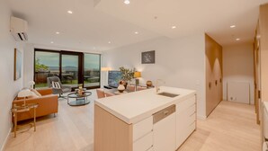 A modern apartment with a kitchen island, dining area, and a large window with a view.