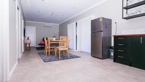 A modern kitchen with a stainless steel refrigerator, wooden dining table, and chairs.