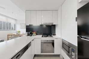 Eine moderne Küche mit weißen Schränken, einem eingebauten Backofen und einem Edelstahl-Kühlschrank.