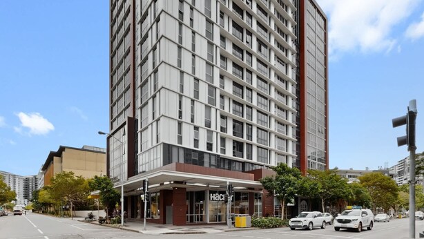 Un edificio moderno de gran altura con una planta baja comercial que alberga un restaurante llamado 'Hacienda'.