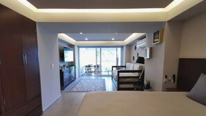 Ein modernes Schlafzimmer mit einem großen Bett, einem Schreibtisch und Blick auf einen Balkon.