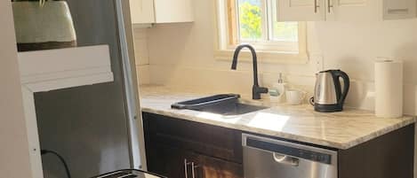 A compact kitchen with a sink, a kettle, and a toaster on a countertop.