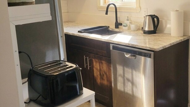 A compact kitchen with a sink, a kettle, and a toaster on a countertop. - Park view home (Vancouver)