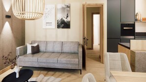 Een moderne woonkamer met een grijze bank, een hanglamp en twee ingelijste foto’s aan de muur.