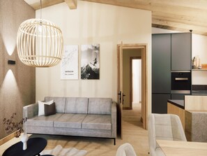 A modern living room with a grey sofa, a hanging light fixture, and two framed pictures on the wall. - Beautiful penthouse in the center of Westendorf. (Westendorf)