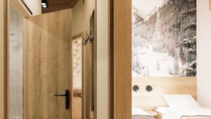 Een houten deur die leidt naar een kamer met een bed en een groot raam met uitzicht op een besneeuwde berg.
